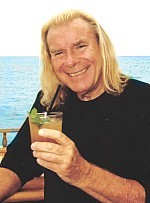Verne Langdon boit un cocktail au bord de l'océan pacifique.